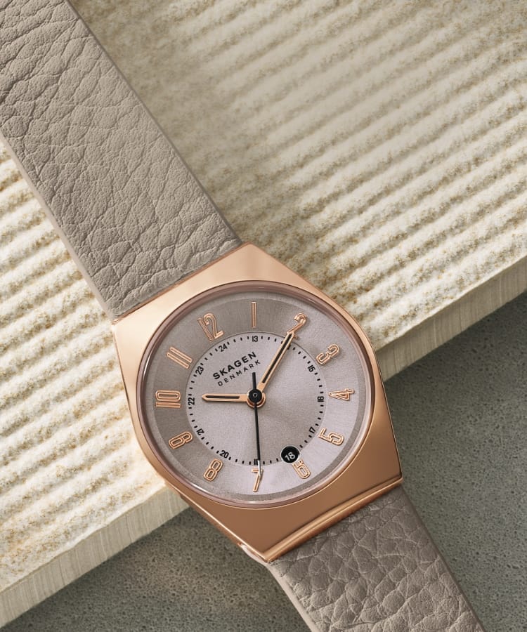 Eine Uhr mit grauem Lederband. Eine Frau mit einer Uhr mit grauem Lederband