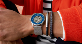 Silver case with matching mesh strap and blue dial. A variety of silver and black bracelets.