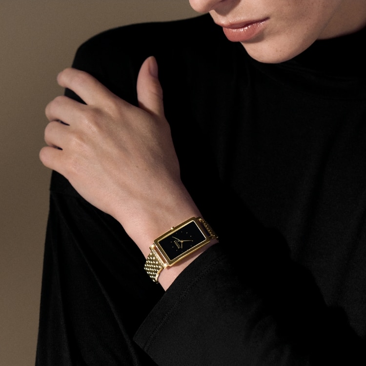 Image of model wearing a black and gold watch