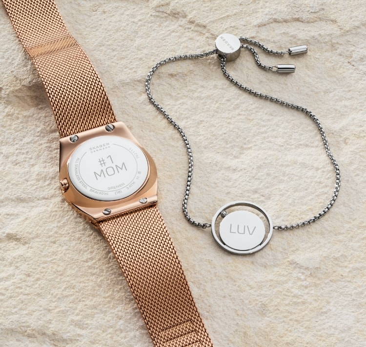 Bild mit einer Uhr und einem Armband im Sand.