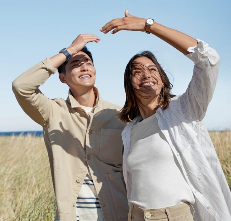 A man wearing a solar watch and a woman wearing a solar watch standing outside in the sun