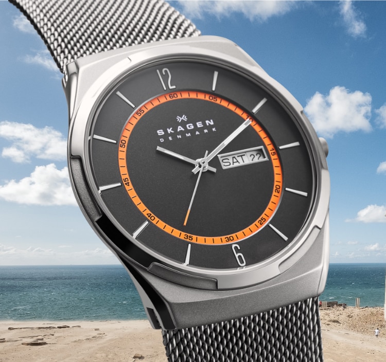 Melbye watch with a gray dial, case, and matching stainless steel strap set against an image of a beach landscape. 