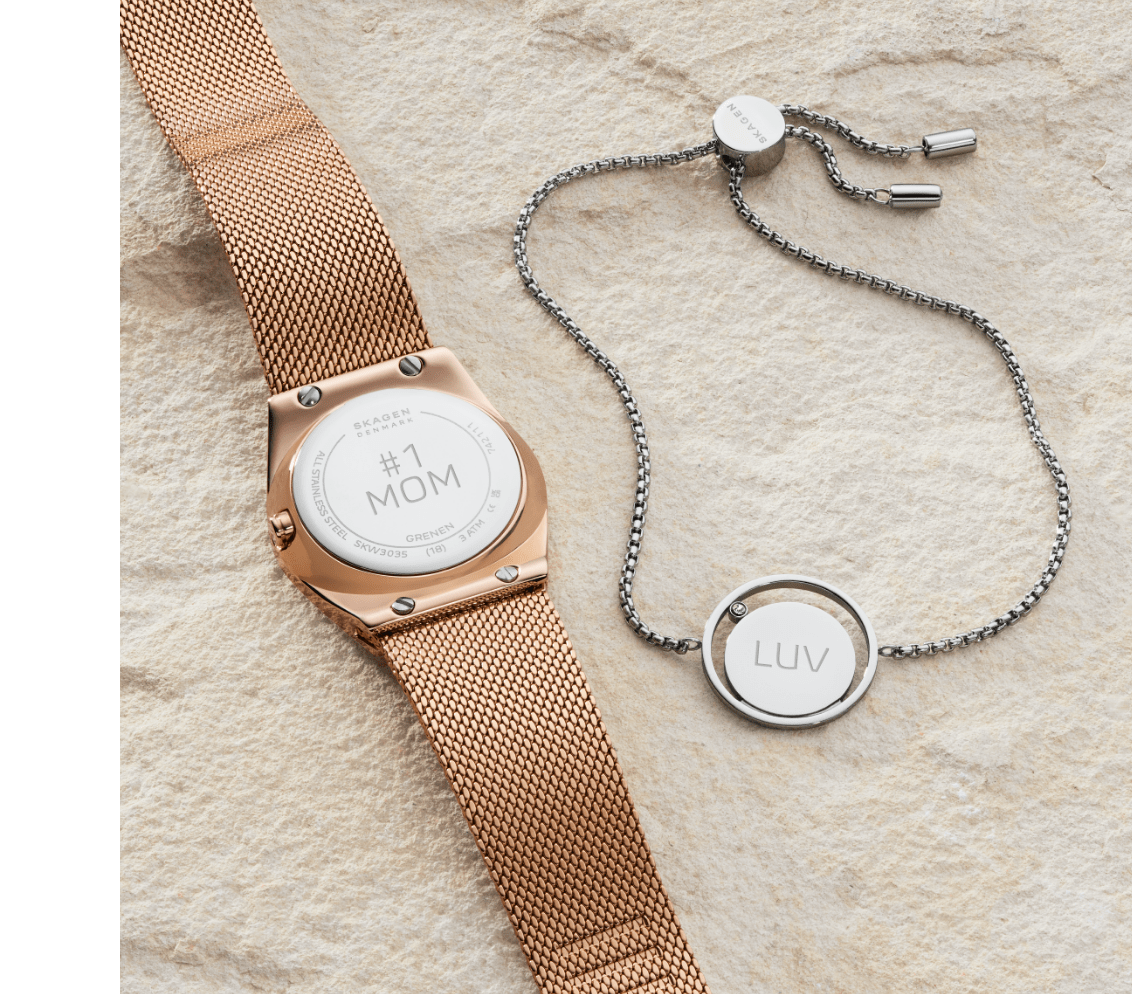 Bild mit einer Uhr und einem Armband im Sand.