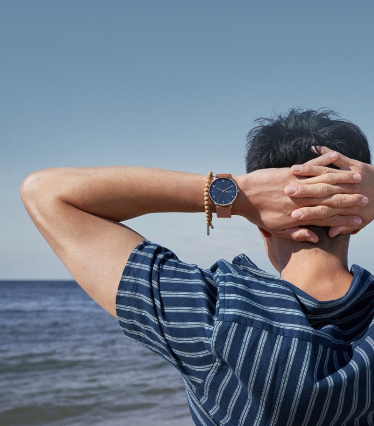 Man on a beach wearing a Skagen watch and bracelet