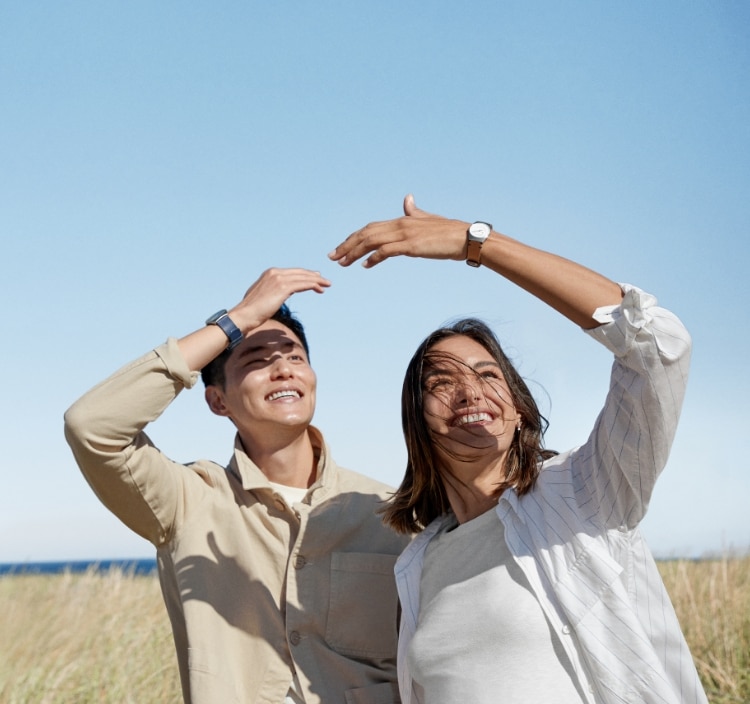 A man and woman in a field wearing Skagen watches