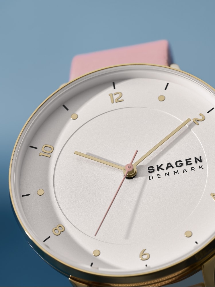 Frau mit Skagen Schmuck und einer Skagen Uhr. Die neue Uhr Riis mit weißem Zifferblatt und rosafarbenem Lederband.