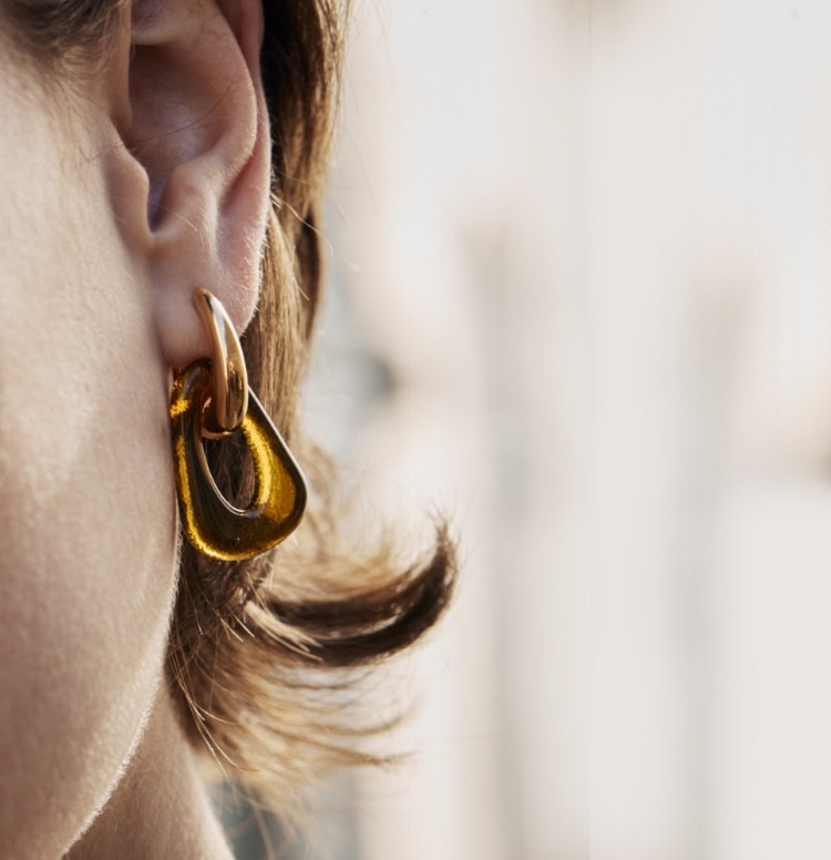Close-up of a woman’s face wearing CLED X SKAGEN earrings