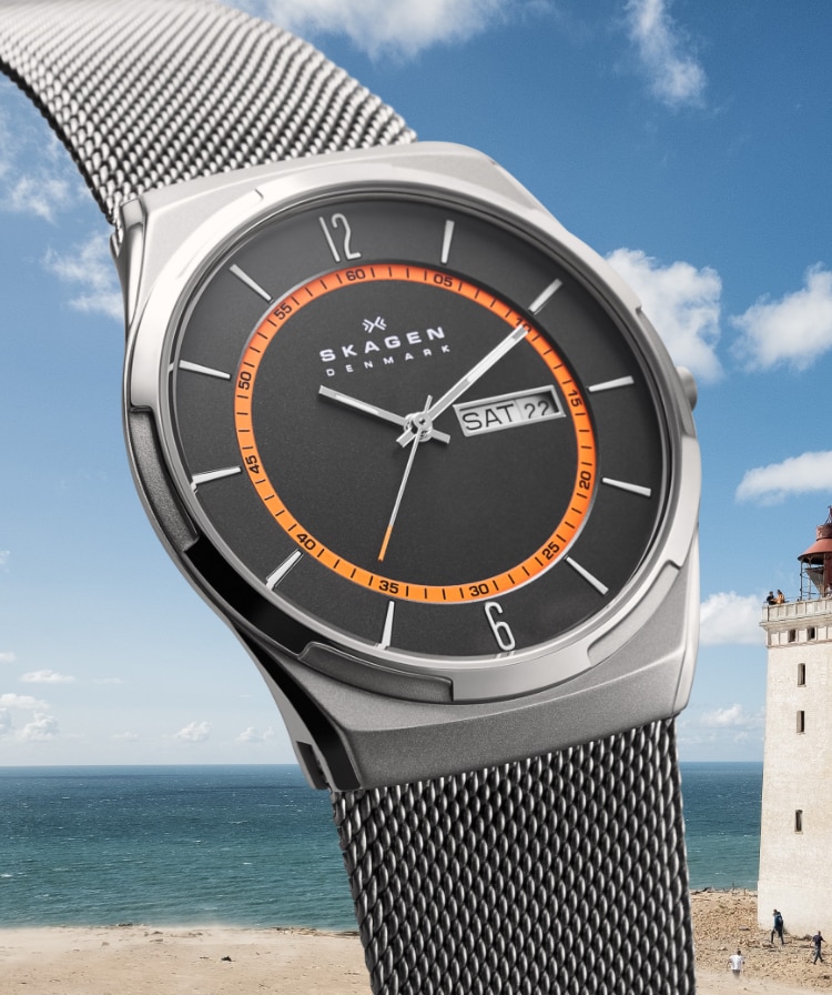 A Skagen Melbye watch with a beach and lighthouse in the background