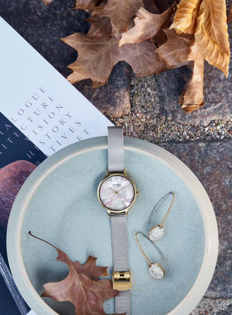 Woman sitting on a bench in Copenhagen. A bowl with a watch and a pair of earrings